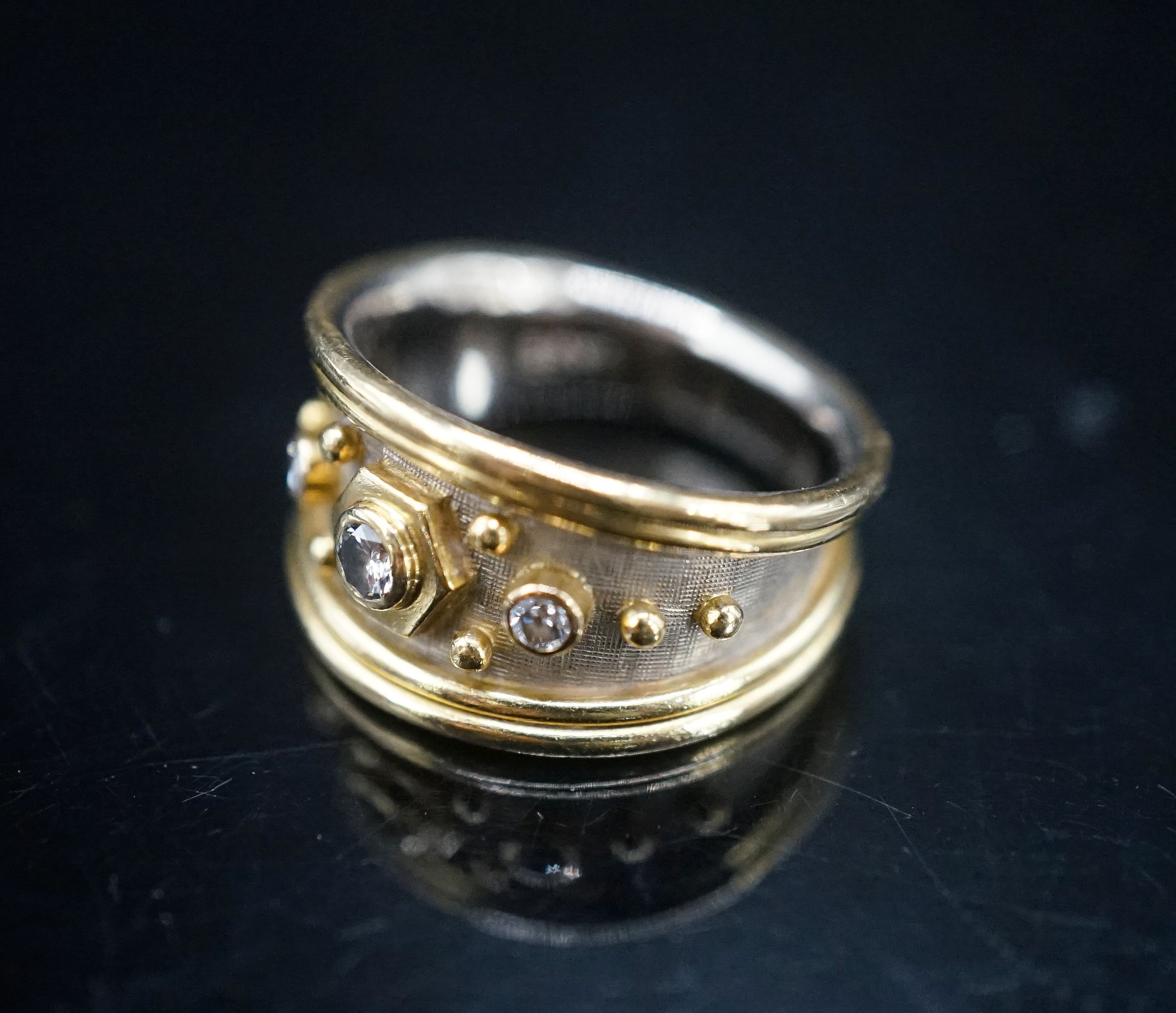 A modern two colour 18ct gold and three stone diamond set dress ring by Elisabeth Gage, size K/L, gross weight 7 grams, with engraved date to shank interior.